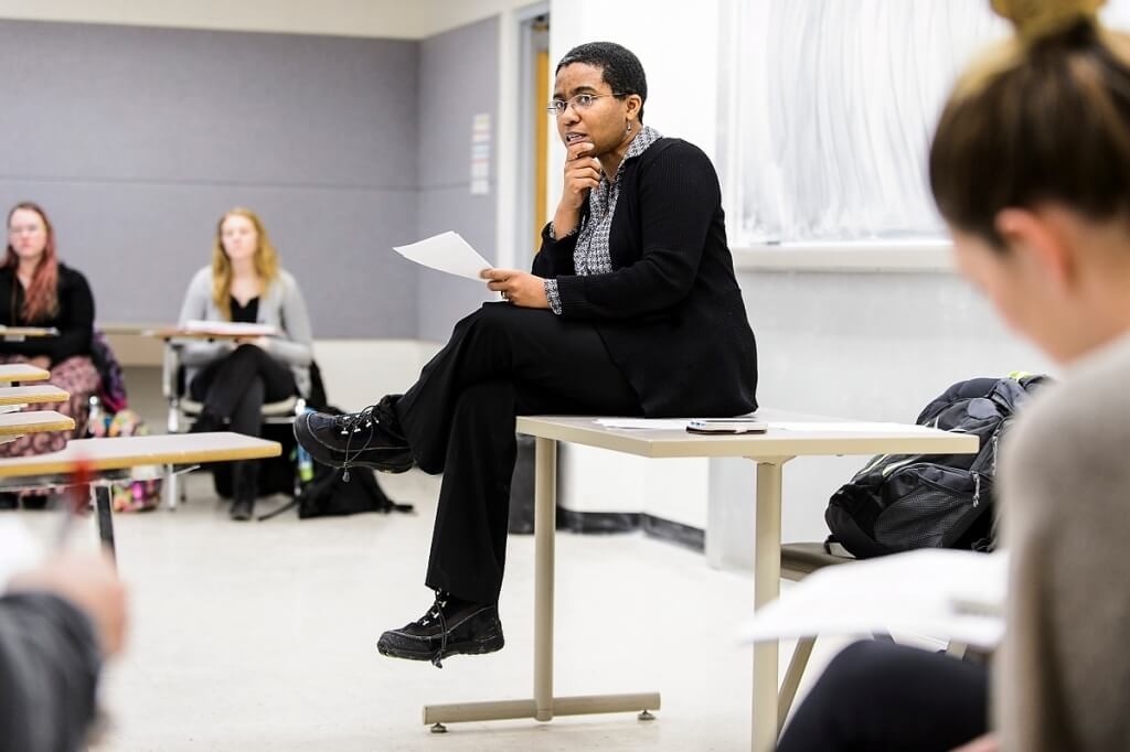 Keisha Lindsay sits on a table as she teaches a class of undergraduate students