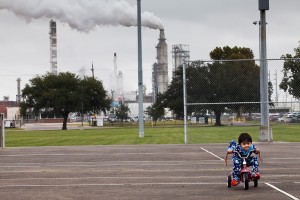 Chrisangel Nieto, age 3, ridea his tricycle in front of the Valero refinery in Houston.